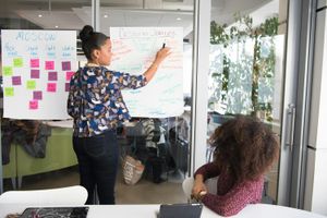 Two women having a meeting in a glass-panelled office.