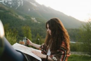 A woman holding a coffee and a map in a mountain landscape